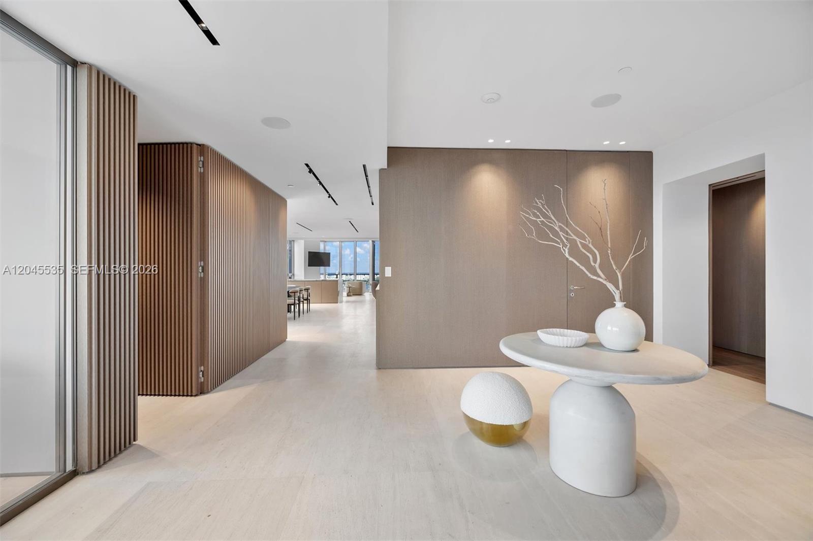 A modern entryway features light wood flooring, a slatted wood wall, and a sculptural console table — 1100 Biscayne Blvd # 3906, Miami FL 33132, MIAMI, FL