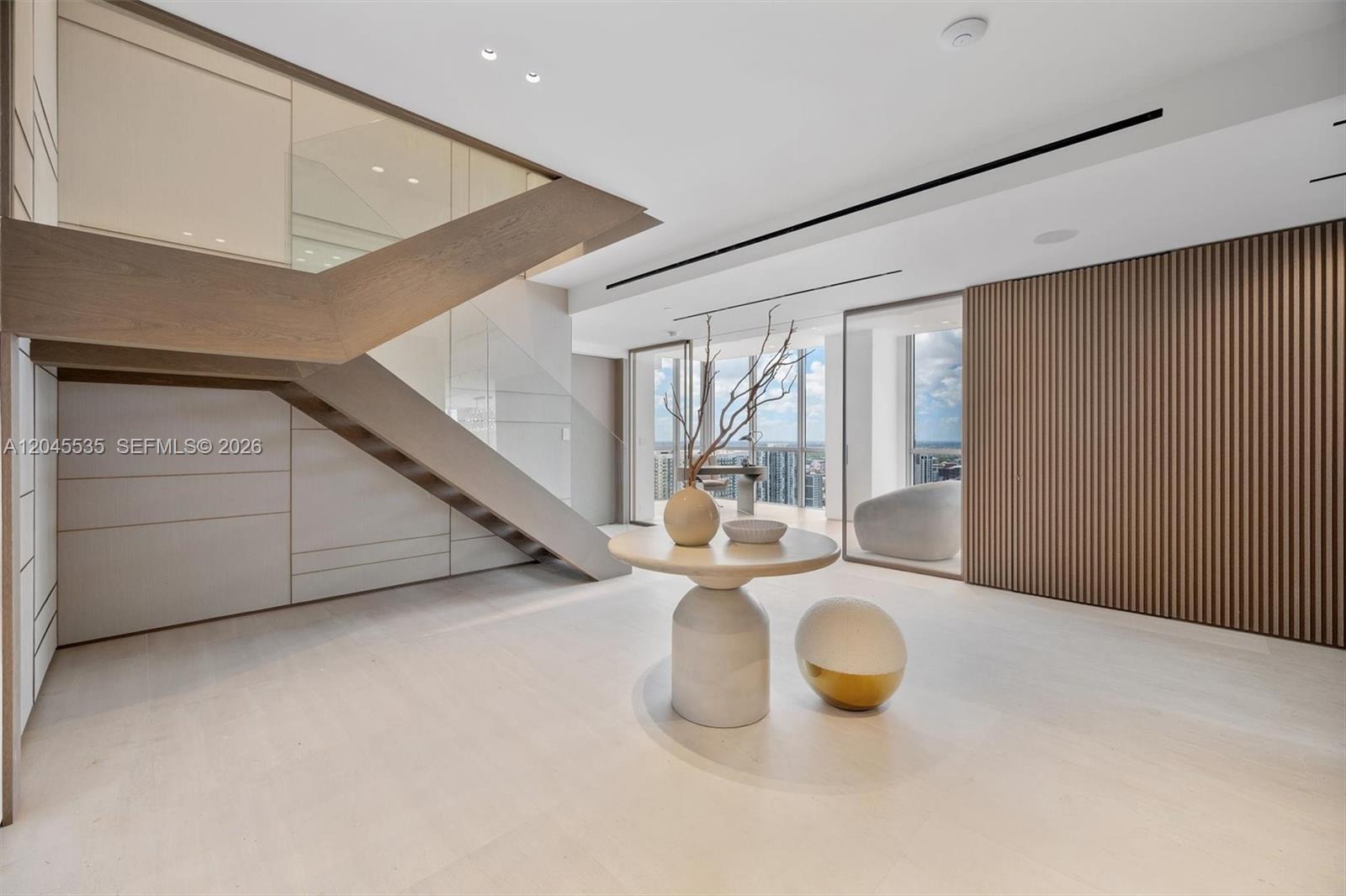 A modern room features a wooden staircase, a round pedestal table, and floor-to-ceiling windows — 1100 Biscayne Blvd # 3906, Miami FL 33132, MIAMI, FL