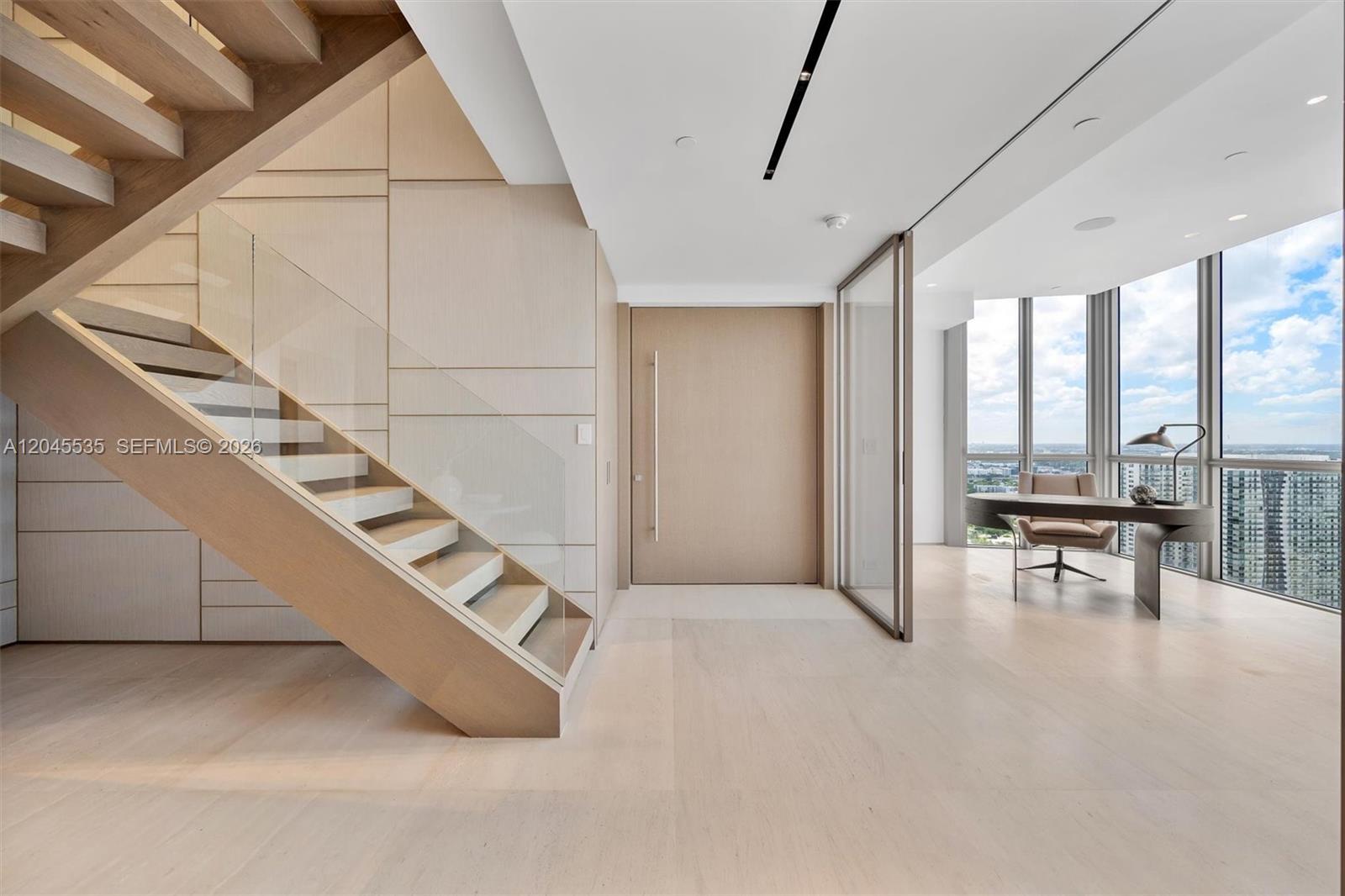 A modern room features a wooden staircase, light wood flooring, and a glass-enclosed office area — 1100 Biscayne Blvd # 3906, Miami FL 33132, MIAMI, FL