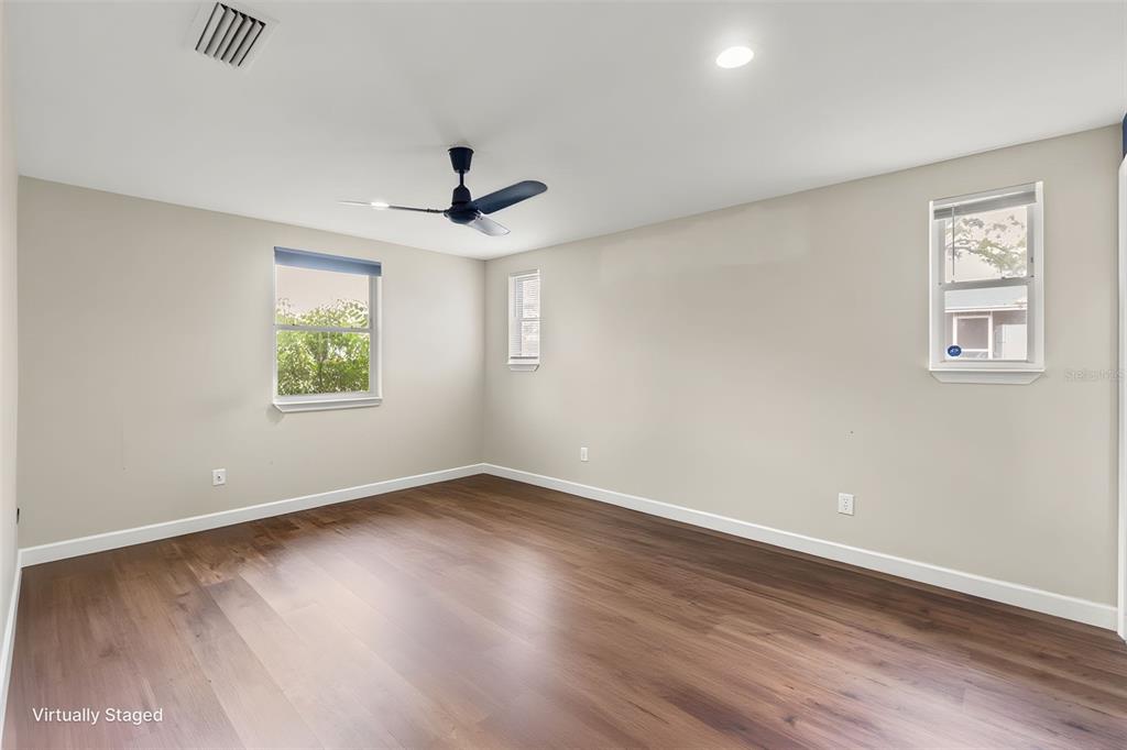 An empty bedroom with light-colored walls, wood-look flooring, a ceiling fan, and two windows — 9658 BAYSIDE COURT, SPRING HILL, FL