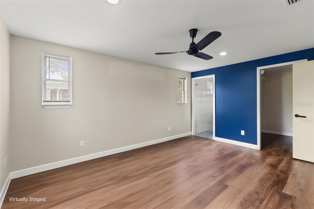 An empty bedroom features wood-look flooring, a ceiling fan, and a blue accent wall — 9658 BAYSIDE COURT, SPRING HILL, FL