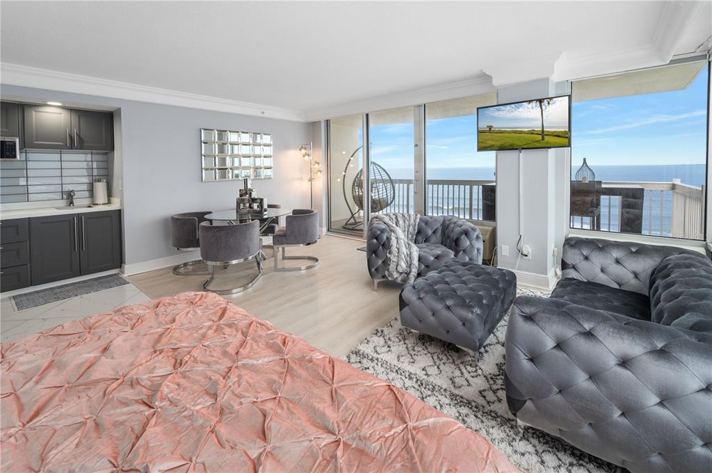 A modern studio apartment features a kitchenette, dining area, living space, and oceanfront balcony views — 2700 N ATLANTIC AVENUE UNIT 1210, DAYTONA BEACH, FL