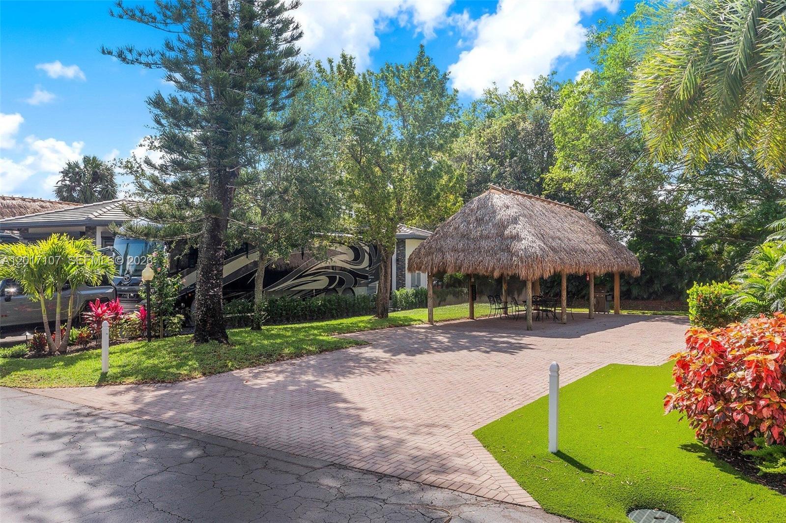 A paved driveway features a thatched-roof tiki hut and a parked recreational vehicle — 22 S Cortez Dr, Margate FL 33068, MARGATE, FL