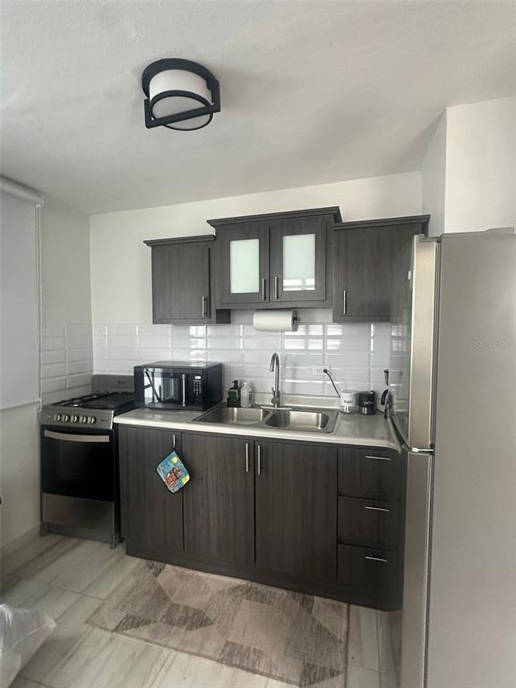 A kitchen features dark wood cabinets, stainless steel appliances, and a white subway tile backsplash — F14, 5013 Calle Colosense URB. EXTENSIÓN ELIZABETH, CABO ROJO, PR