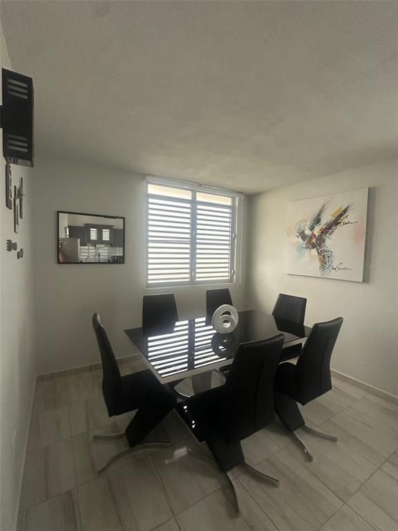 A dining room features a black table with six matching chairs and a large abstract painting — F14, 5013 Calle Colosense URB. EXTENSIÓN ELIZABETH, CABO ROJO, PR