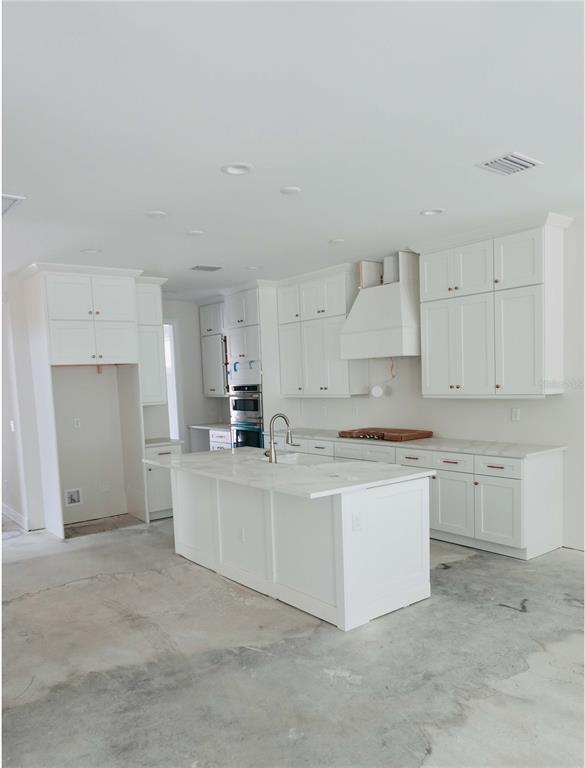 A kitchen island with a farmhouse sink and white cabinets sits in an unfinished room — 3905 W TACON STREET, TAMPA, FL