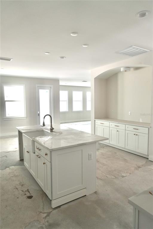 A kitchen features white cabinets, a marble-topped island, and an unfinished concrete floor — 3905 W TACON STREET, TAMPA, FL