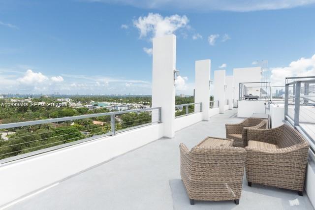 A rooftop terrace features wicker patio furniture, a metal railing, and views of the city — 8101 Biscayne Blvd # 414, Miami FL 33138, MIAMI, FL