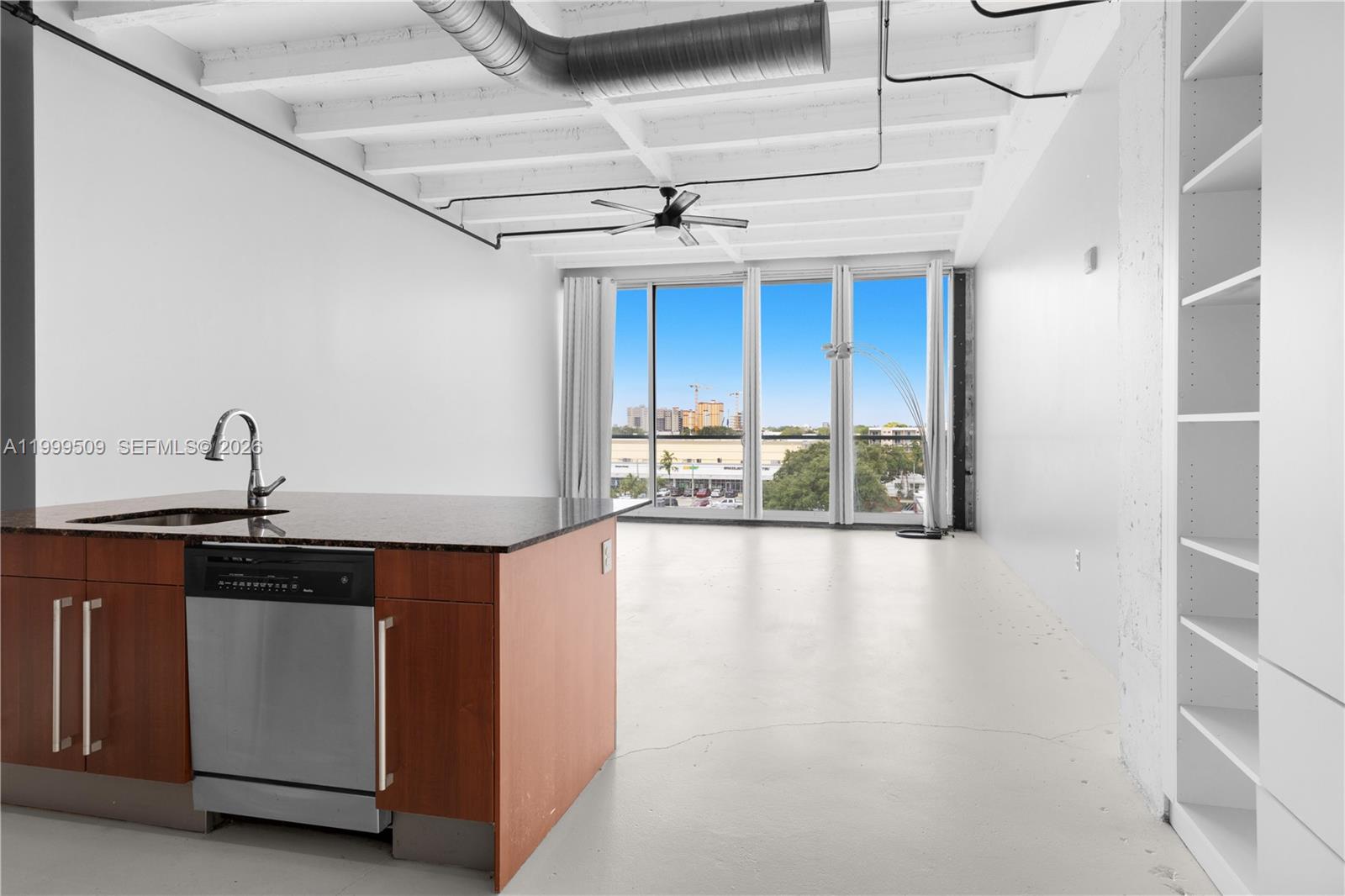 A modern apartment features an open kitchen island, exposed ceiling beams, and floor-to-ceiling windows — 8101 Biscayne Blvd # 414, Miami FL 33138, MIAMI, FL