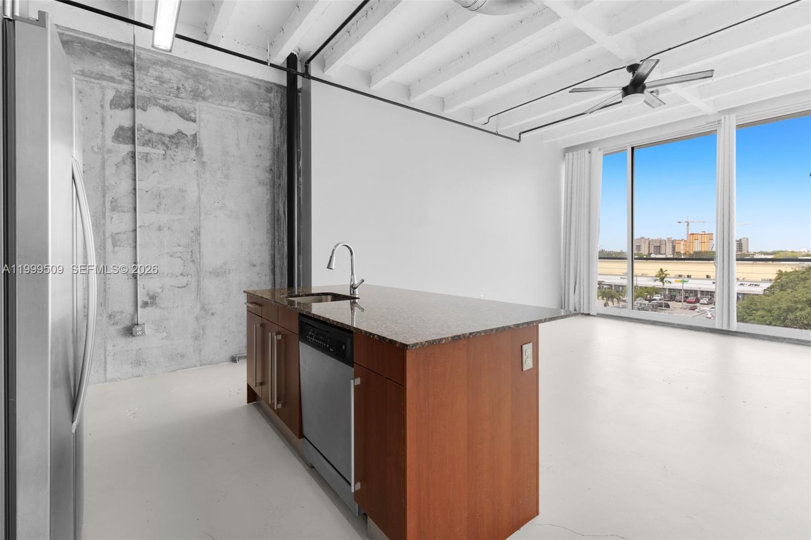 An industrial-style kitchen features a wooden island, concrete wall, and large windows with city views — 8101 Biscayne Blvd # 414, Miami FL 33138, MIAMI, FL