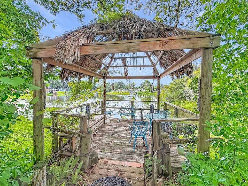 A wooden gazebo with a thatched roof sits on a deck overlooking a lake — 10116 E GULF TO LAKE HIGHWAY, INVERNESS, FL