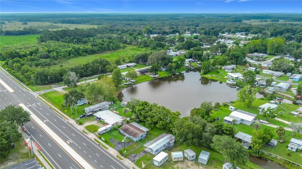 An aerial view shows a small lake surrounded by residential properties and a nearby highway — 10116 E GULF TO LAKE HIGHWAY, INVERNESS, FL