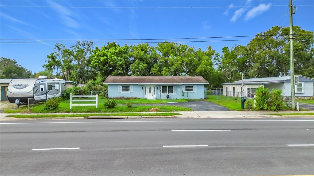 A light blue, single-story house sits behind a paved road with a camper parked nearby — 10116 E GULF TO LAKE HIGHWAY, INVERNESS, FL
