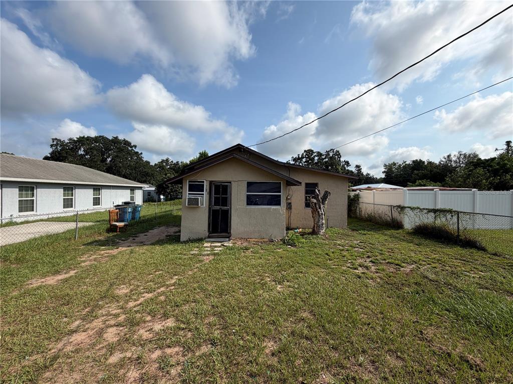 A small, single-story house with a tan stucco exterior stands in a grassy yard — 114 W MURPHY STREET, DAVENPORT, FL