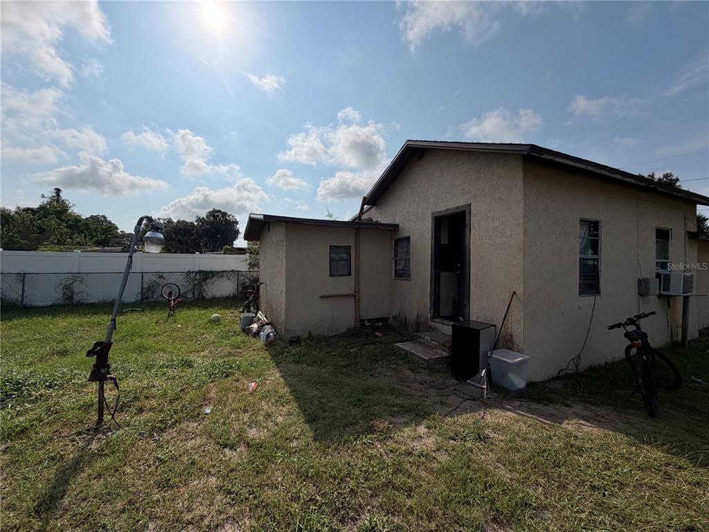 The exterior of a single-story house features stucco walls, a small porch, and a backyard — 114 W MURPHY STREET, DAVENPORT, FL