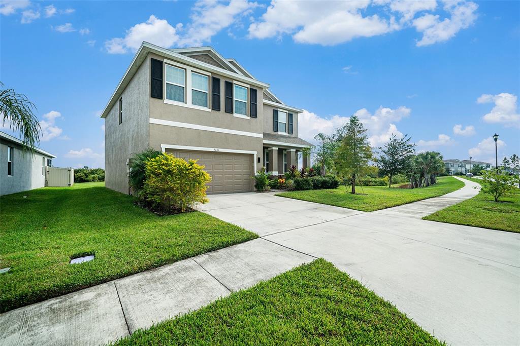 A two-story suburban house with a tan stucco exterior and a two-car garage — 5430 THISTLE FIELD COURT, WESLEY CHAPEL, FL