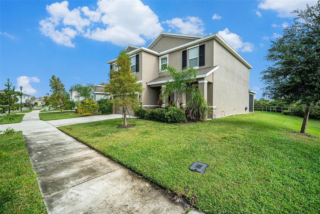 A two-story suburban house with a beige stucco exterior and a concrete sidewalk — 5430 THISTLE FIELD COURT, WESLEY CHAPEL, FL