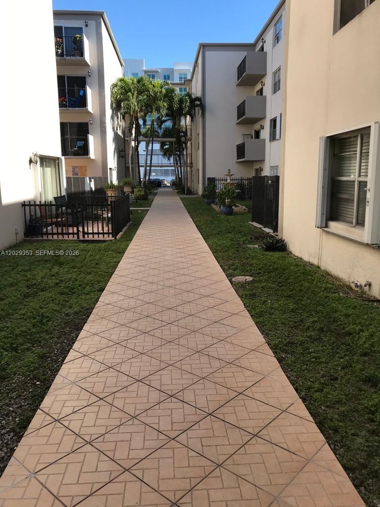 A paved walkway leads between two multi-story apartment buildings with balconies and palm trees — 5505 NW 7th St # W417, Miami FL 33126, MIAMI, FL