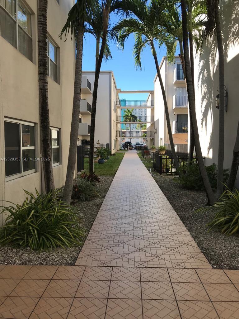 A paved walkway leads between two apartment buildings lined with palm trees — 5505 NW 7th St # W417, Miami FL 33126, MIAMI, FL