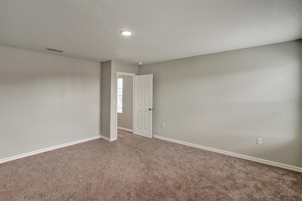 An empty bedroom with gray walls, brown carpeting, and a white door leading to another room — 4903 MAINSAIL STREET, HAINES CITY, FL