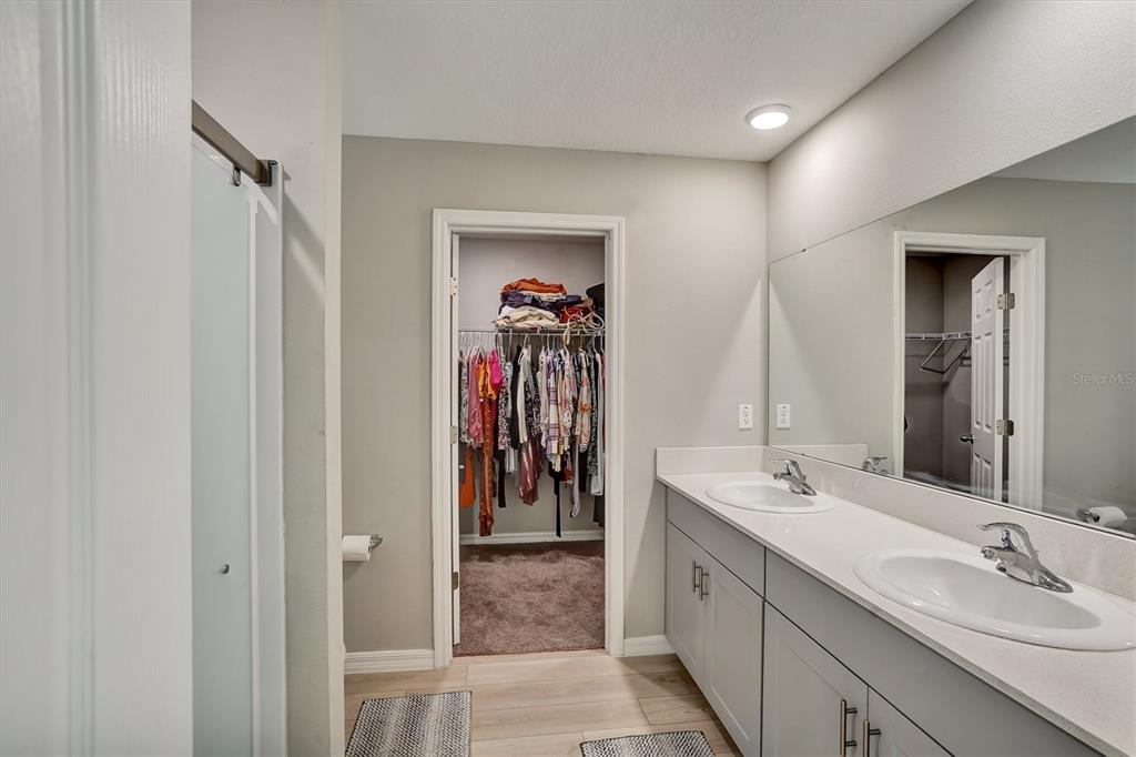 A bathroom features a double vanity with gray cabinets, a large mirror, and a walk-in closet — 4903 MAINSAIL STREET, HAINES CITY, FL