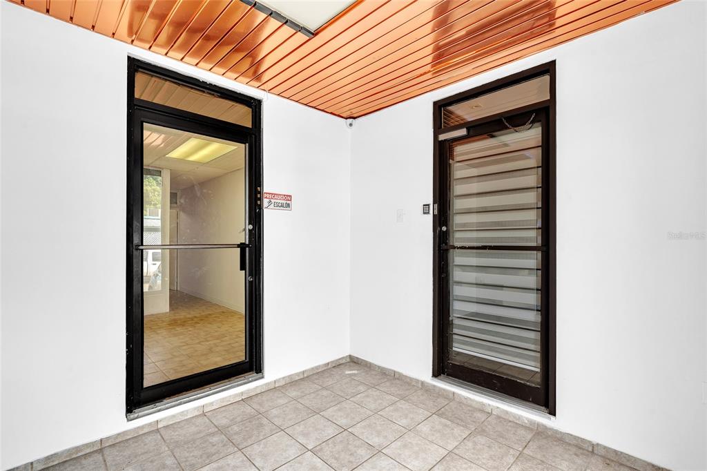 An outdoor entryway features two glass doors, white walls, and a wood-paneled ceiling — 1000 8SE ANDALUCÍA, PUERTO NUEVO, PR
