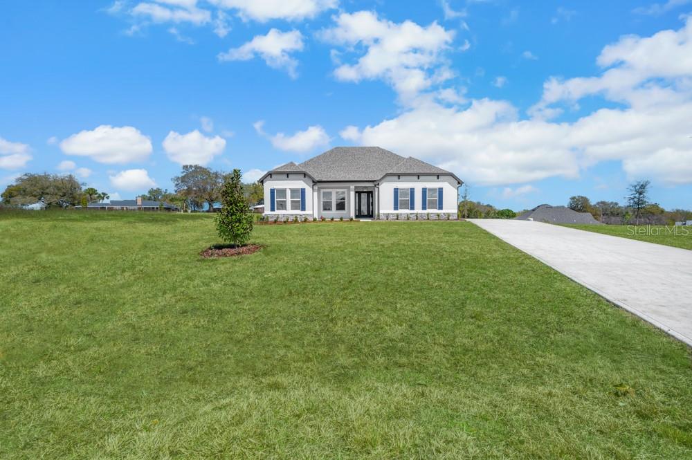 A single-story house with a white exterior, blue shutters, and a concrete driveway — 3840 SADDLE HILL TRAIL, FRUITLAND PARK, FL