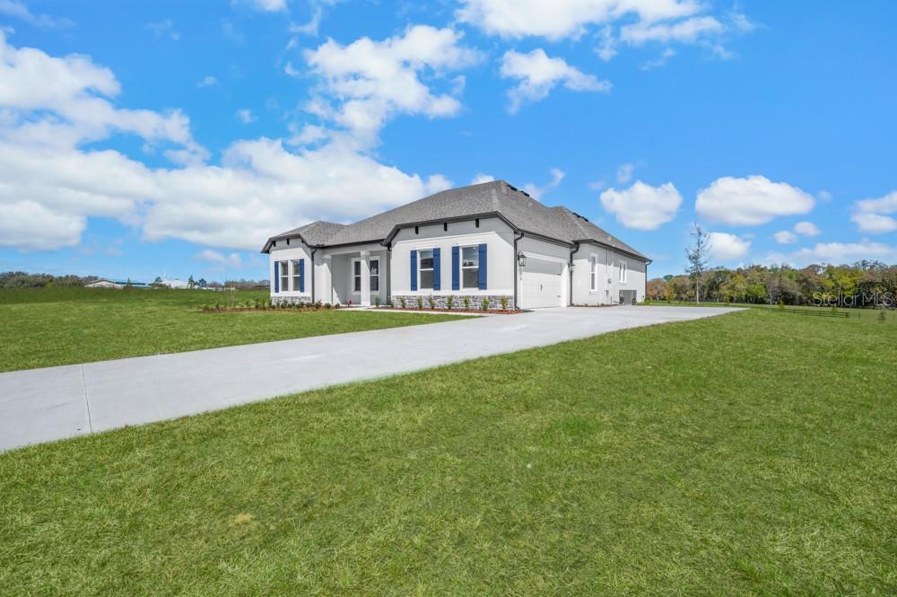 A single-story house with a white exterior, blue shutters, and a concrete driveway — 3840 SADDLE HILL TRAIL, FRUITLAND PARK, FL
