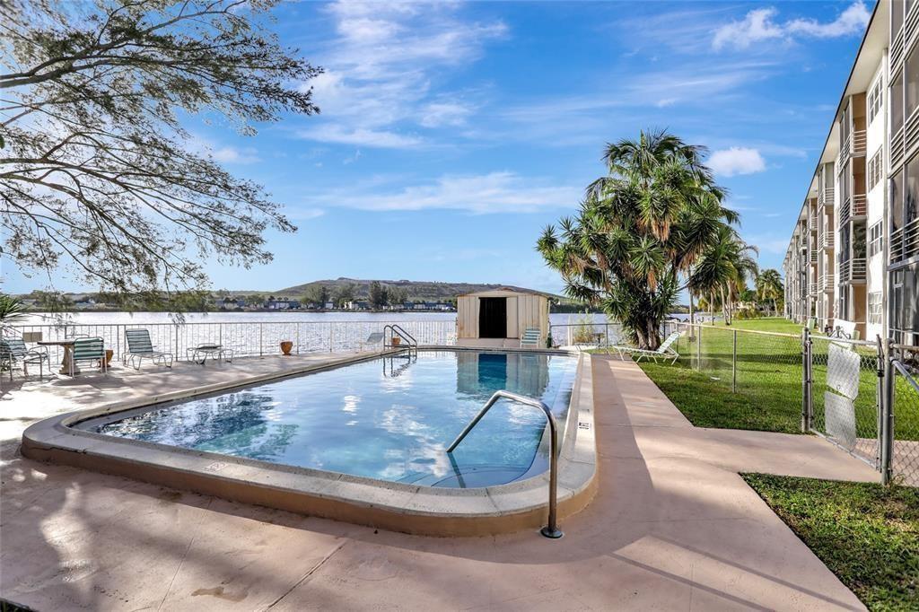 An outdoor swimming pool sits beside a multi-story apartment building overlooking a lake — 4311 Crystal Lake Drive # 421, Pompano Beach FL 33064, POMPANO BEACH, FL