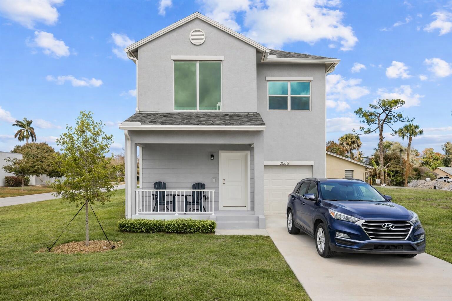 A two-story gray house with a front porch and a blue car in the driveway — 2575 SE Bonita Street, Stuart FL 34997, STUART, FL