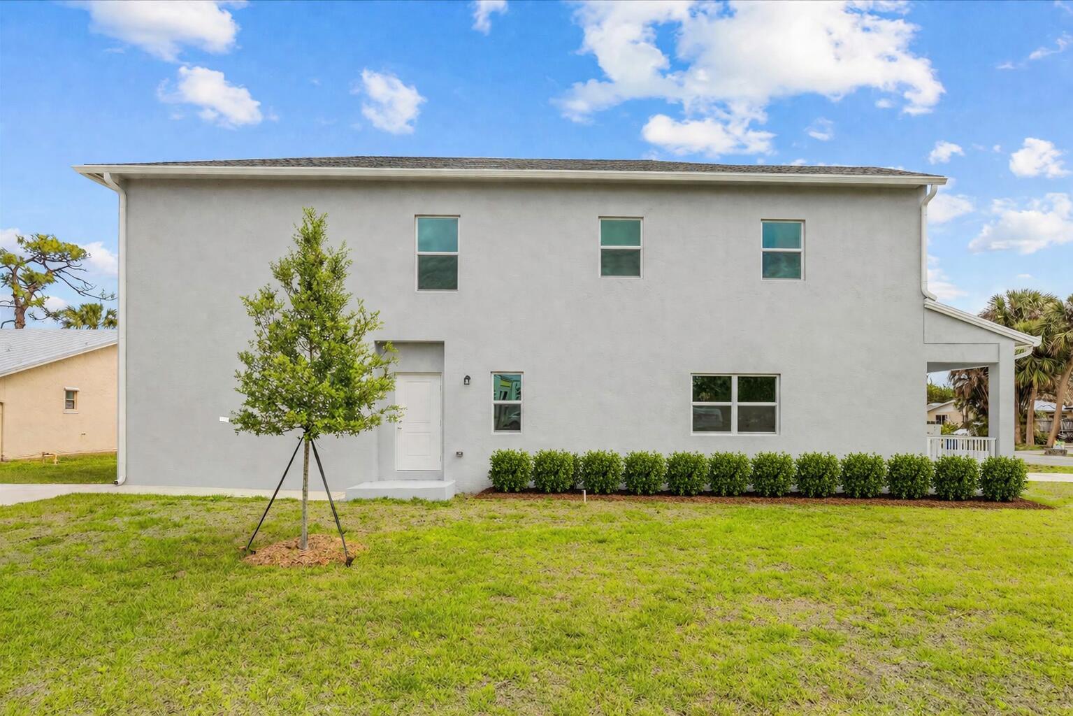 A two-story gray stucco house features a front door, several windows, and a small tree — 2575 SE Bonita Street, Stuart FL 34997, STUART, FL