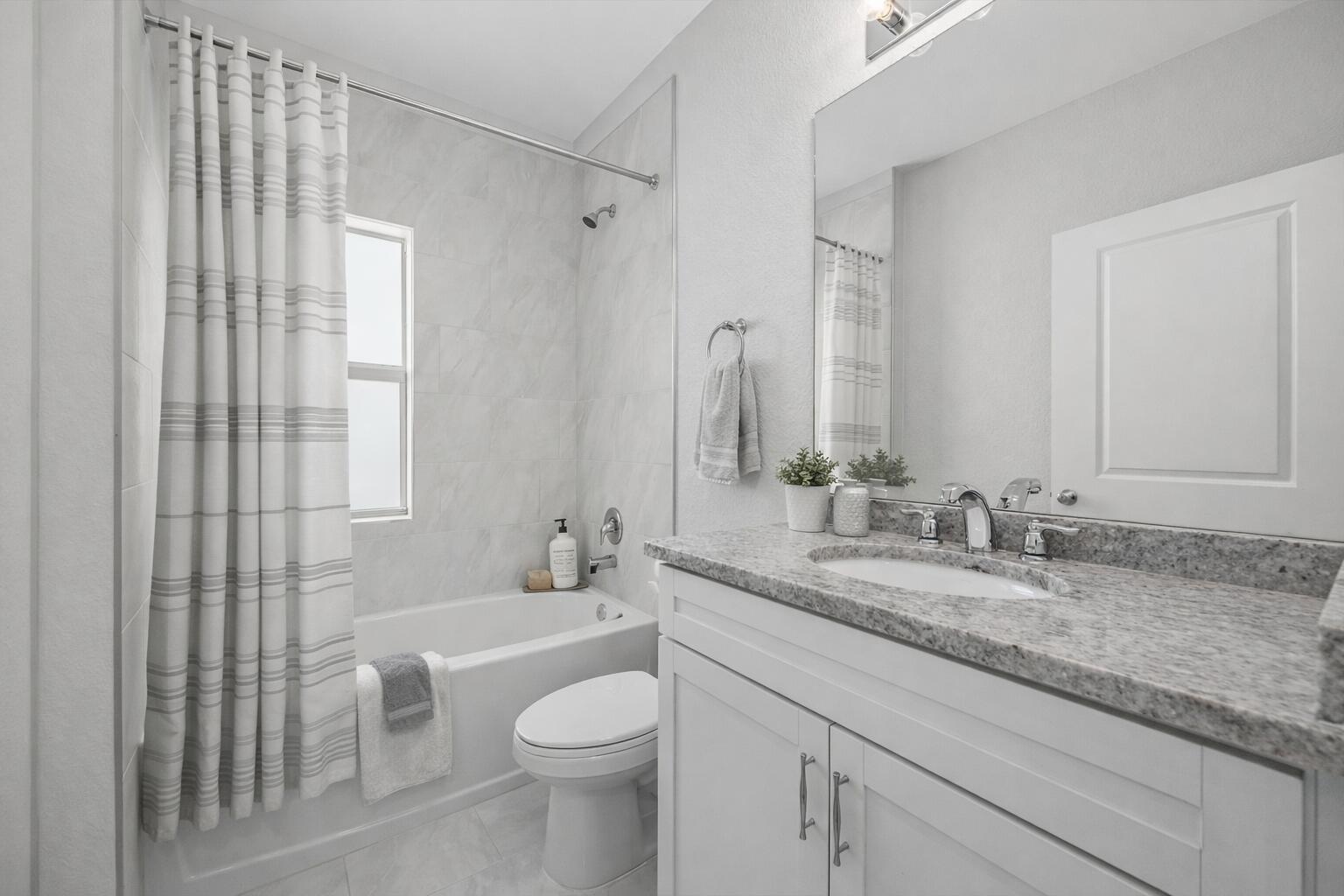 A bathroom features a white vanity with a granite countertop, a toilet, and a tub-shower — 2575 SE Bonita Street, Stuart FL 34997, STUART, FL