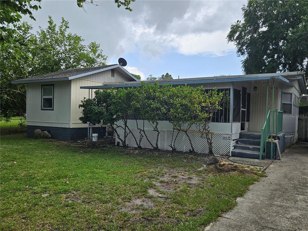 A single-story house with a screened-in porch, lattice skirting, and a concrete driveway — 472 BRYANT STREET, ORMOND BEACH, FL