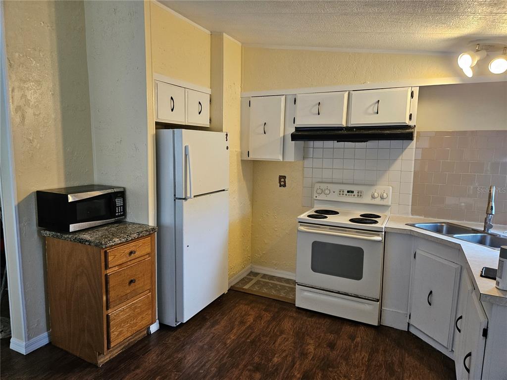 A kitchen features white cabinets, a white refrigerator, a white stove, and wood-look flooring — 472 BRYANT STREET, ORMOND BEACH, FL