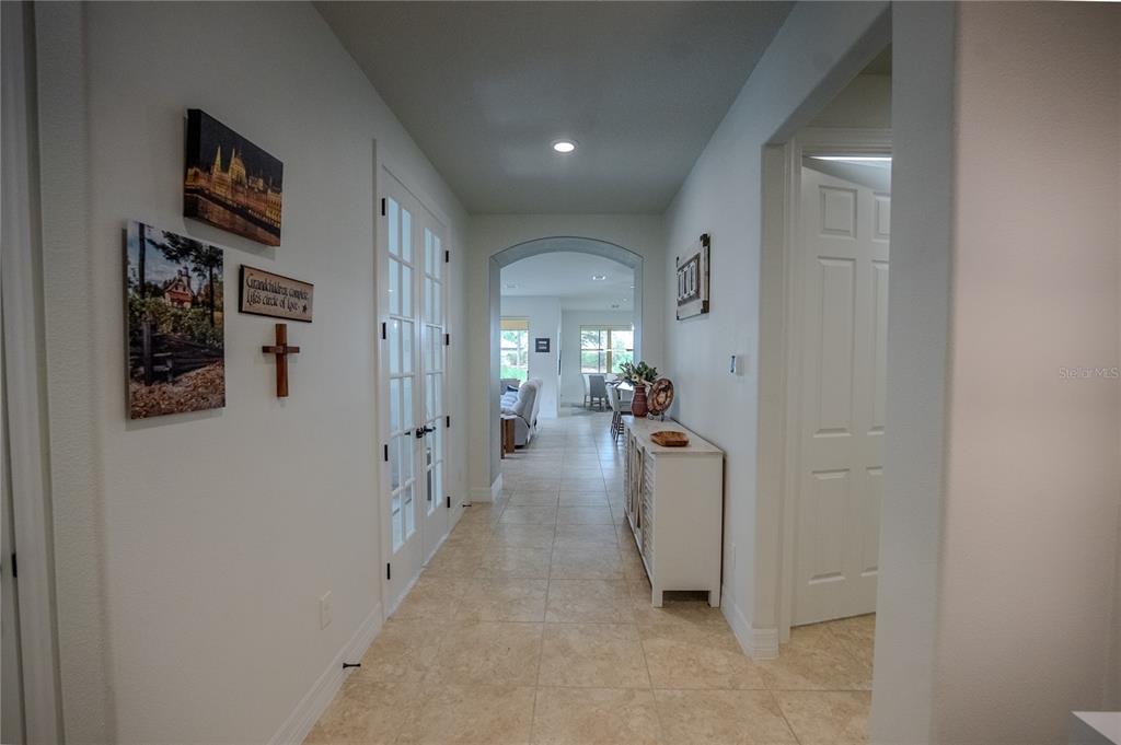 A tiled hallway leads through an arched doorway toward a bright living and dining area — 9576 SW 65TH PLACE, OCALA, FL