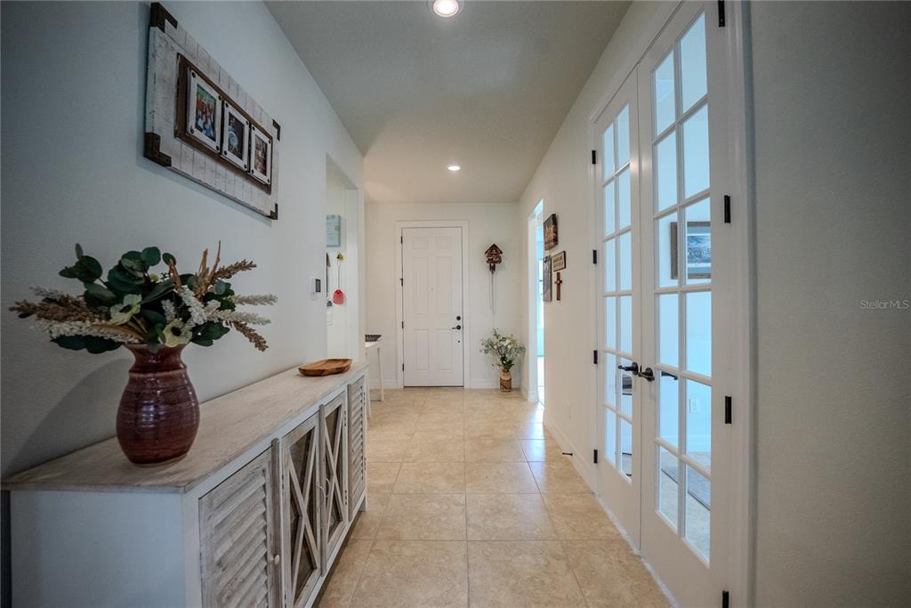 A hallway features tile flooring, a white console table, and French doors leading to another room — 9576 SW 65TH PLACE, OCALA, FL