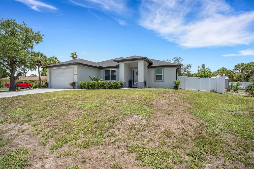 A single-story house with a gray exterior, a two-car garage, and a large front lawn — 9169 CLEWISTON TERRACE, ENGLEWOOD, FL