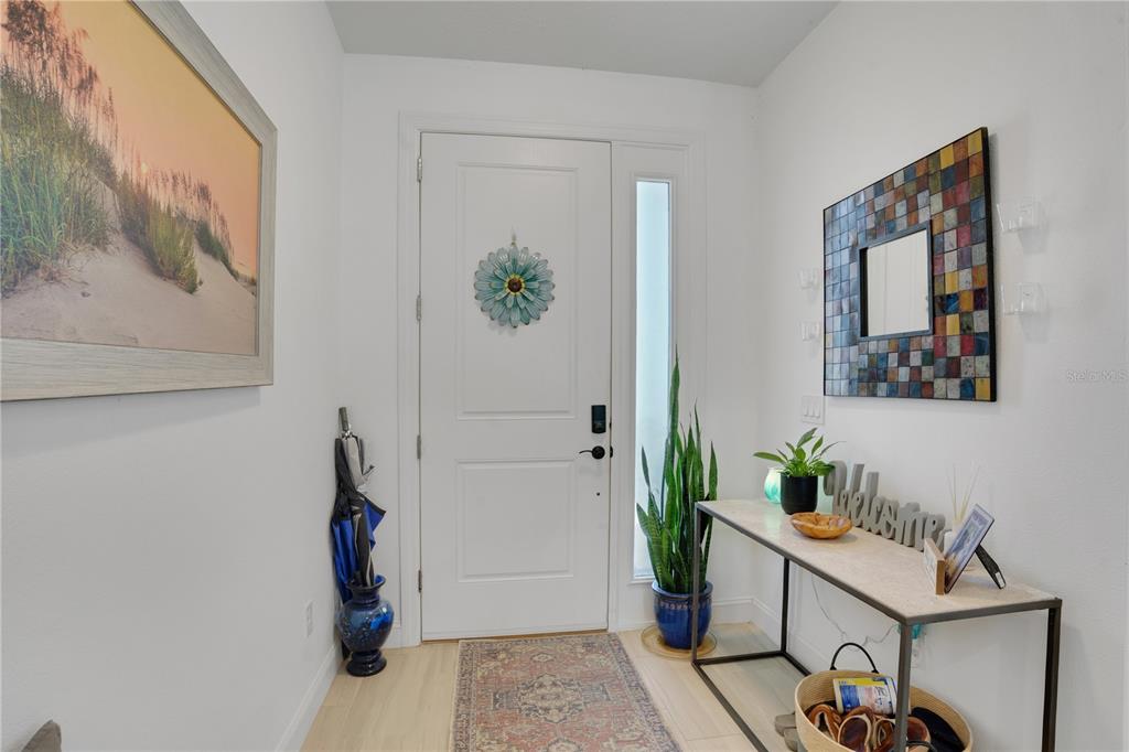 An entryway features a white front door, a console table, a mirror, and decor — 9169 CLEWISTON TERRACE, ENGLEWOOD, FL