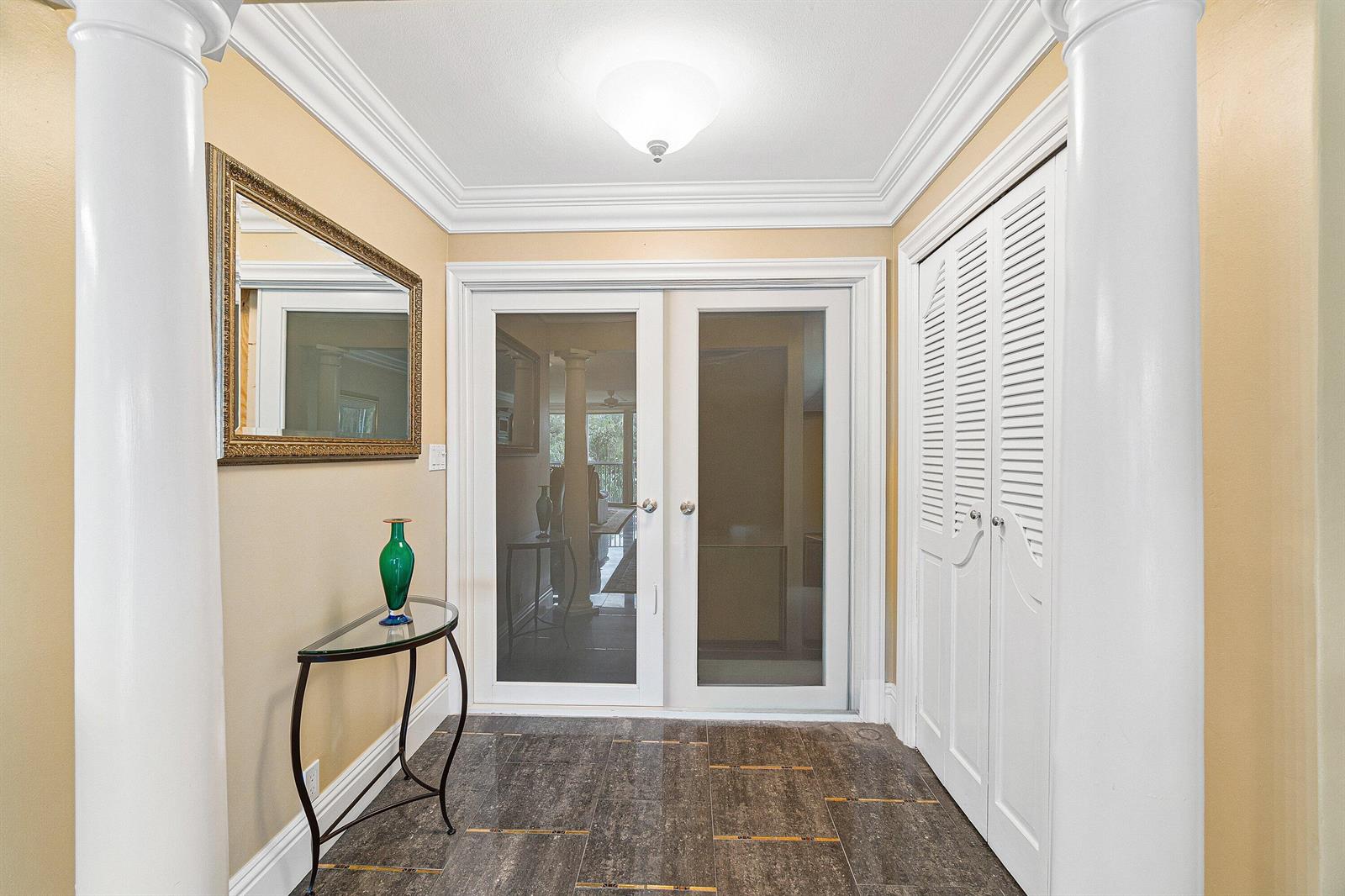 A foyer features a glass-topped console table, white columns, tiled flooring, and double glass doors — 300 E Royal Palm Road # 0350, Boca Raton FL 33432, BOCA RATON, FL