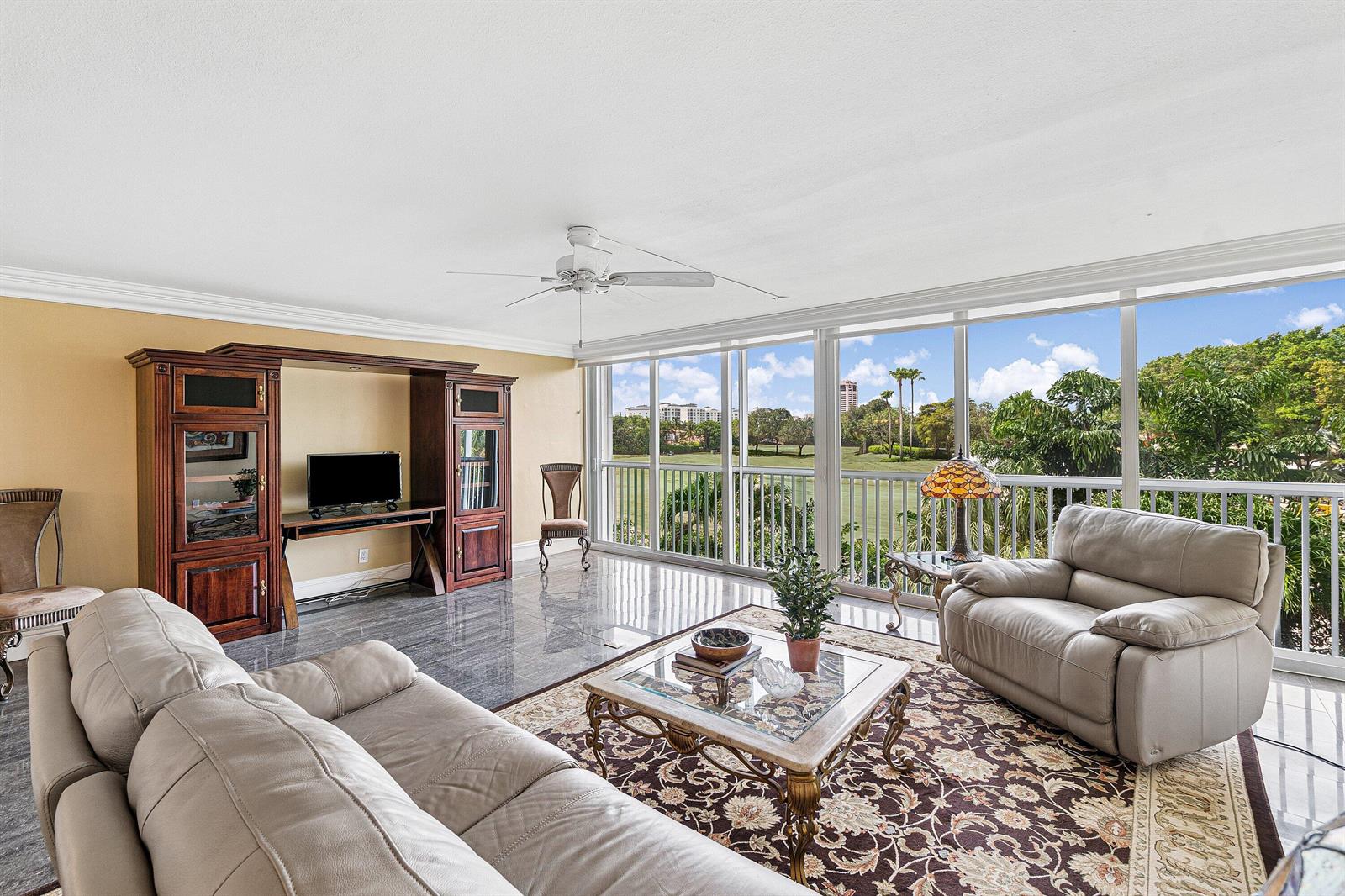 A living room with a leather sofa, glass coffee table, and floor-to-ceiling windows overlooking greenery — 300 E Royal Palm Road # 0350, Boca Raton FL 33432, BOCA RATON, FL
