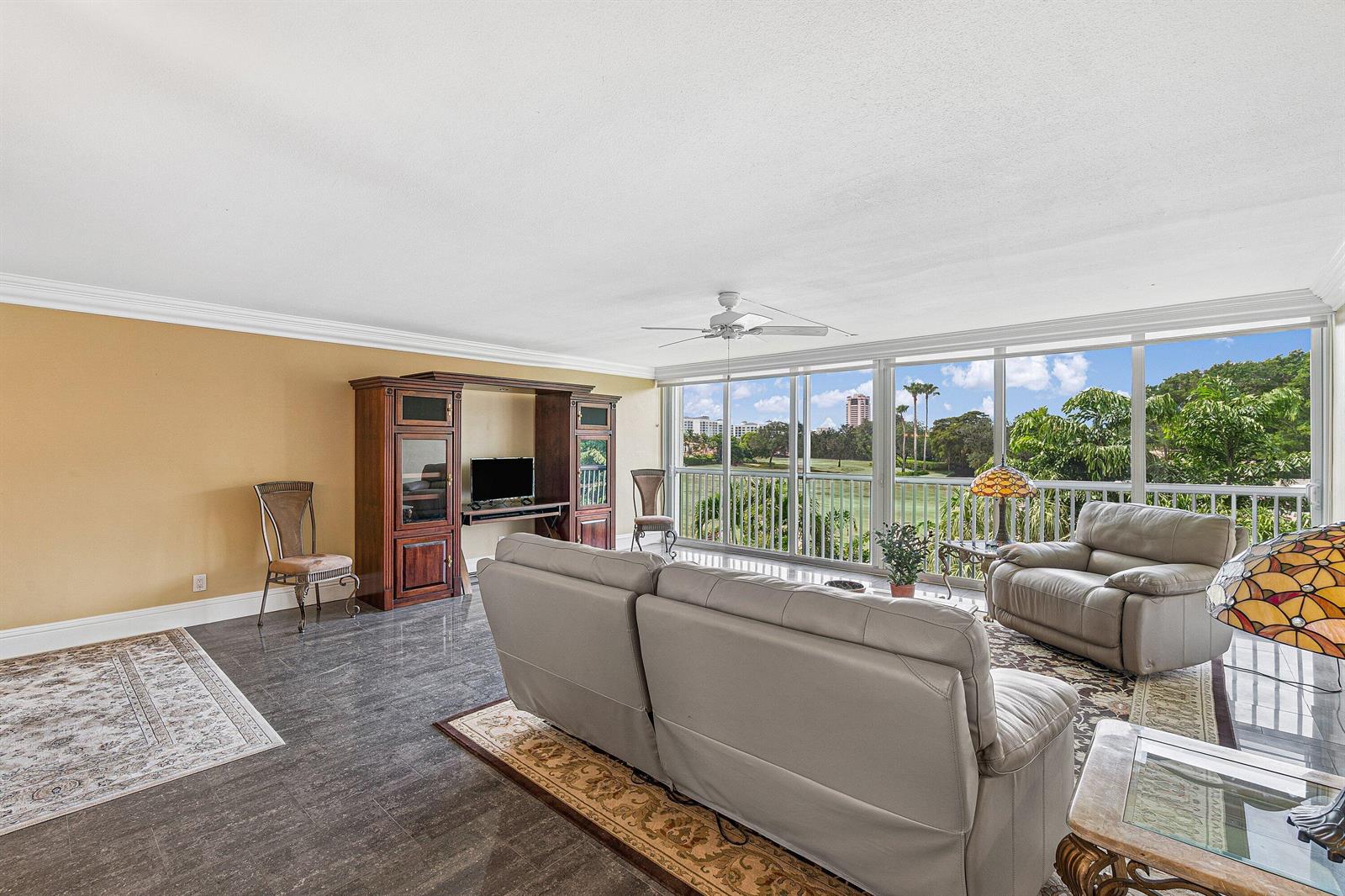 A living room features tile floors, a wooden entertainment center, and a balcony overlooking greenery — 300 E Royal Palm Road # 0350, Boca Raton FL 33432, BOCA RATON, FL