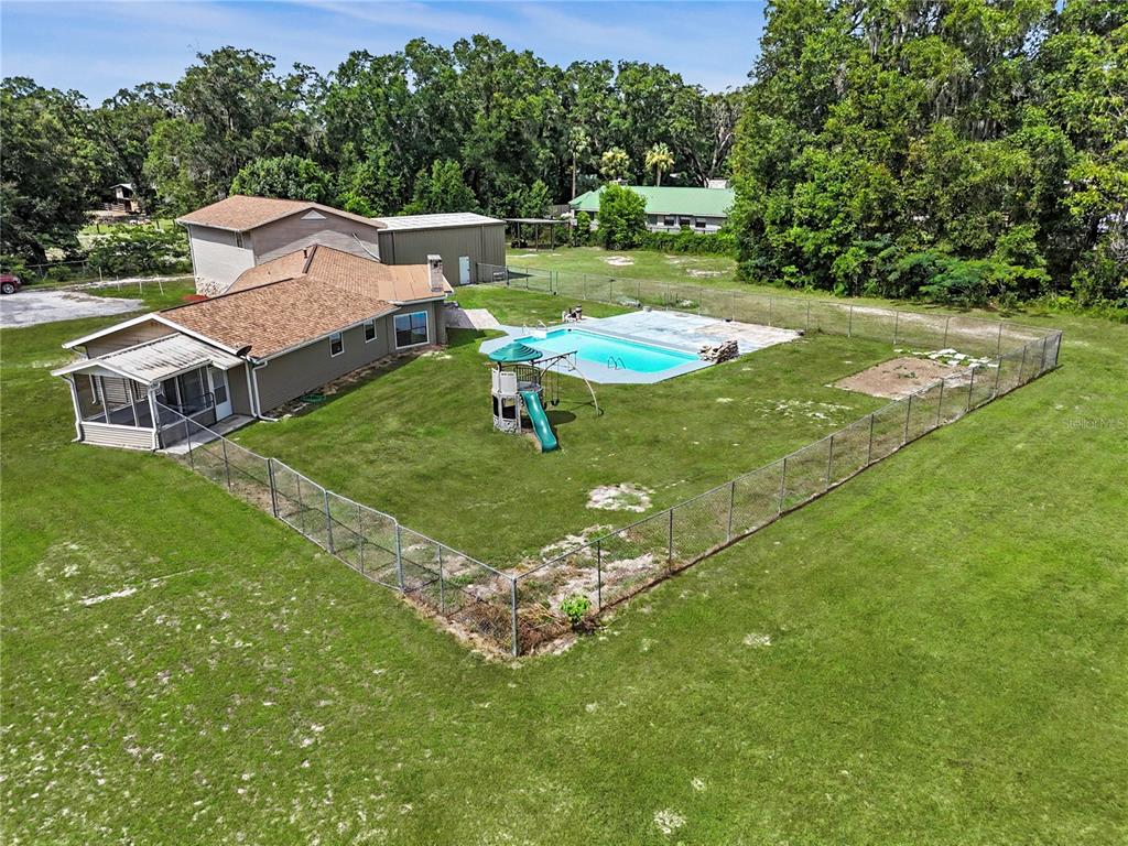 An aerial view shows a house with a fenced backyard, swimming pool, and playground equipment — 2809 NE 49TH STREET, OCALA, FL