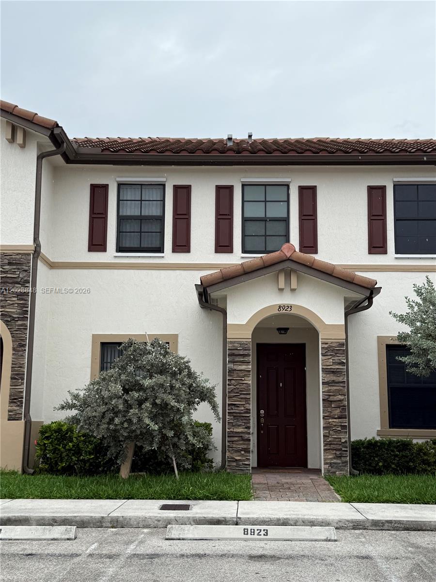 A two-story townhouse exterior features a brown front door, stone accents, and dark shutters — 8923 W 35th Ave, Hialeah FL 33018, HIALEAH, FL