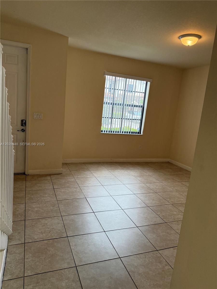 An empty room features beige tile flooring, light-colored walls, and a window with security bars — 8923 W 35th Ave, Hialeah FL 33018, HIALEAH, FL