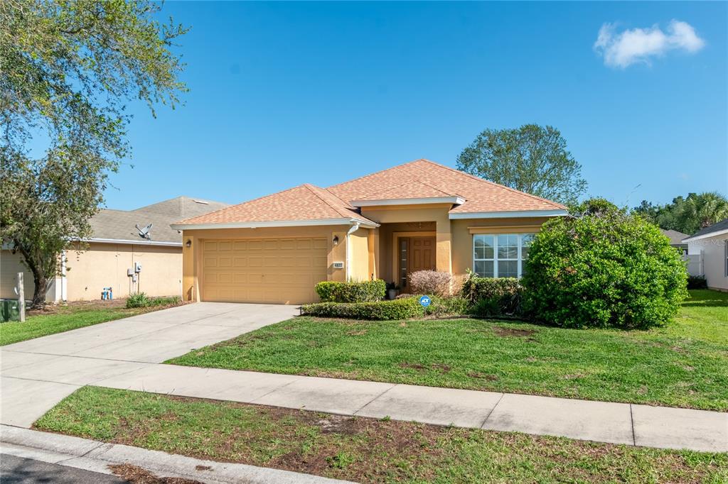 A single-story house with a tan stucco exterior, a two-car garage, and a shingled roof — 4923 SW 40TH LANE, OCALA, FL