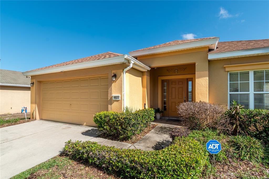 A single-story house with a tan stucco exterior, a two-car garage, and a front entrance — 4923 SW 40TH LANE, OCALA, FL