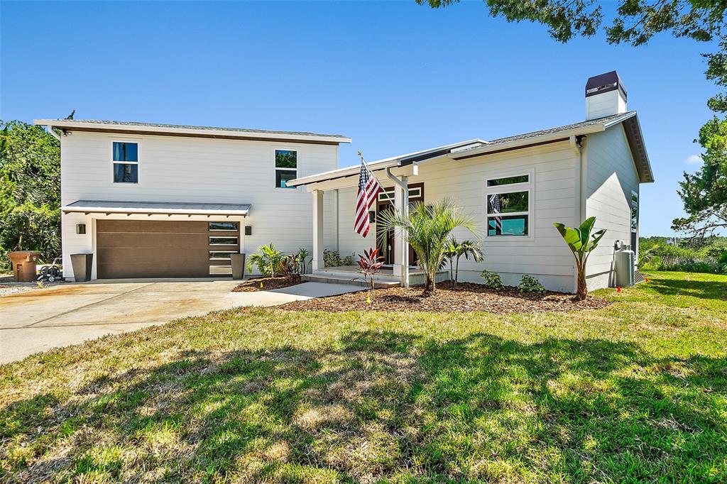 A two-story white house with a brown garage door and a front porch with landscaping — 644 RIVERVIEW ROAD, FLAGLER BEACH, FL
