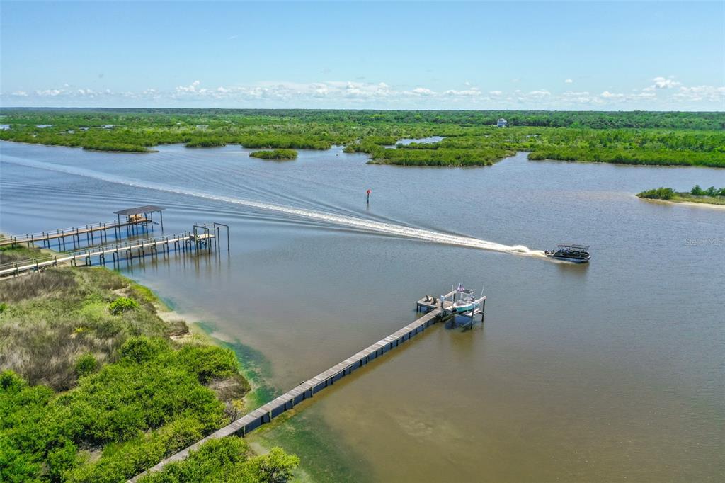 An aerial view shows a boat traveling on a waterway past two wooden docks — 644 RIVERVIEW ROAD, FLAGLER BEACH, FL