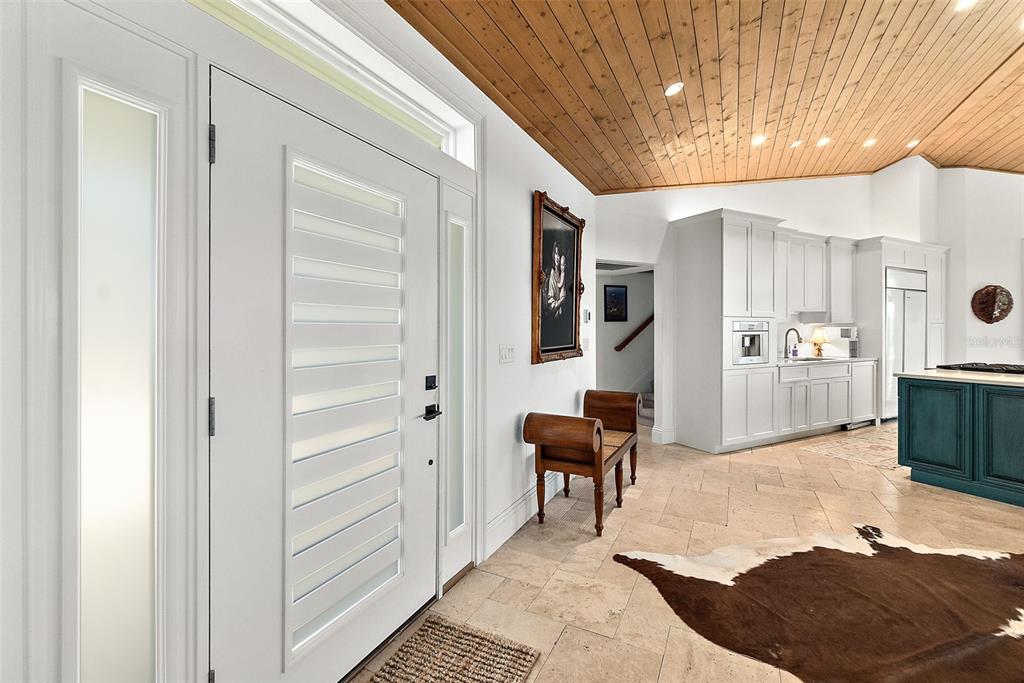 An entryway with a white front door, tile floors, and a wood-paneled vaulted ceiling — 644 RIVERVIEW ROAD, FLAGLER BEACH, FL