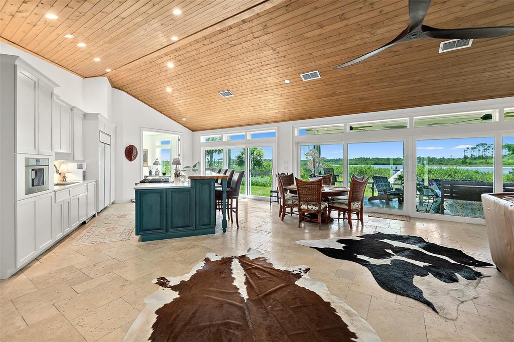 An open-concept kitchen and dining area features a wood-paneled vaulted ceiling and large glass doors — 644 RIVERVIEW ROAD, FLAGLER BEACH, FL